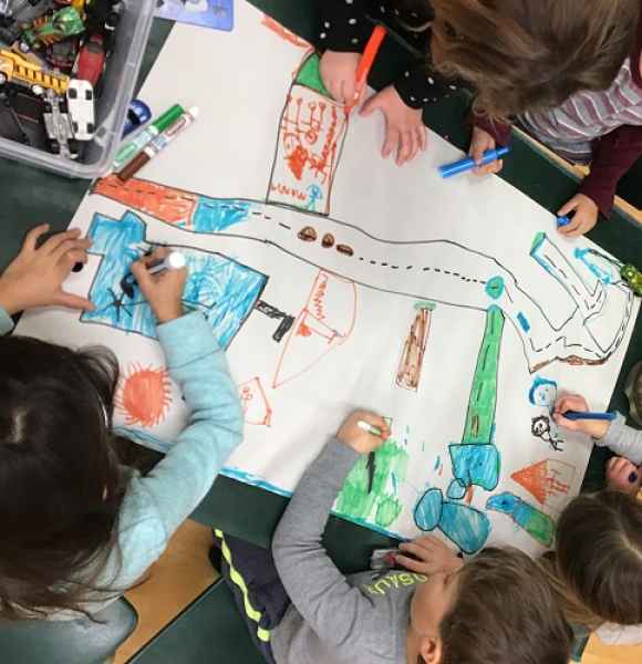 group drawing a large picture together using markers